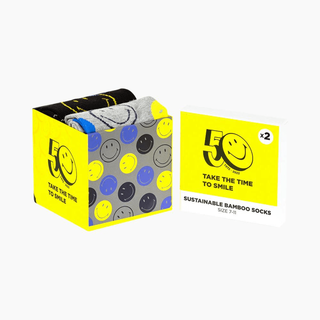 Stewarts Menswear Bamboozled socks 2 pack gift box. This Gift Box is the perfect gift, featuring two pairs of novelty crew socks packaged in a matching Gift Box.  Bamboozld Gift Boxes have a vibrant collection of quirky bamboo-blend socks which pack a playful punch. Theme is Smiley. Includes one x black socks and one by grey socks with smiley faces all over. Image is of box only, yellow with smiley faces.