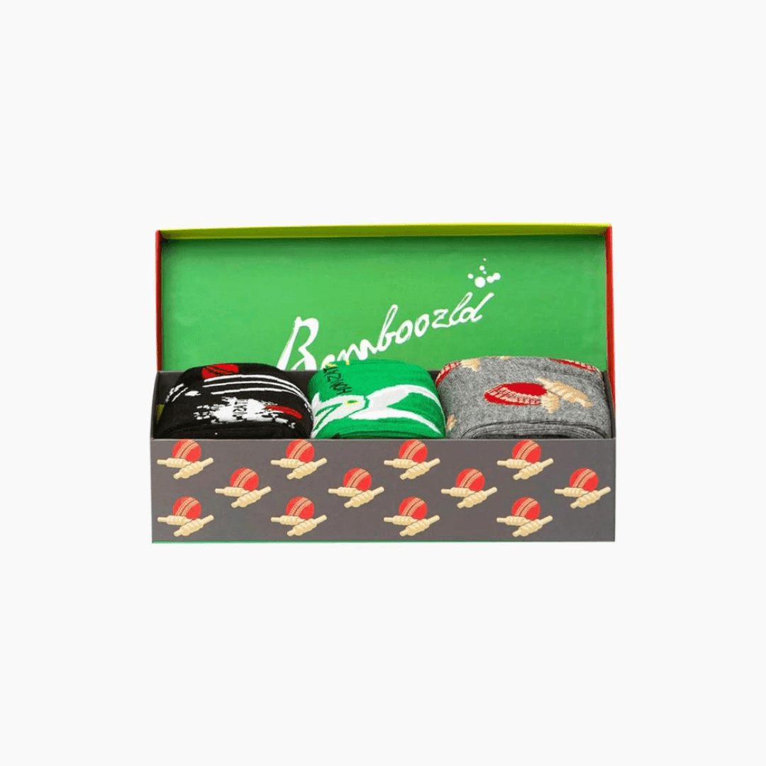 Stewarts Menswear Bamboozled socks 3 pack gift box. This Gift Box is the perfect gift, featuring three pairs of novelty crew socks packaged in a matching Gift Box. Bamboozld Gift Boxes have a vibrant collection of quirky bamboo-blend socks which pack a playful punch. Theme is cricket with one x green socks, 1 x grey socks and 1 x black socks featuring different cricket print on each pair. Image is of 3 x socks packed into gift box.