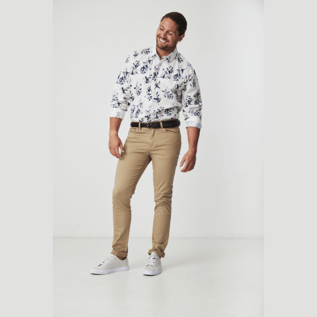 Stewarts Menswear Blackwood Apparel Perry Long Sleeve shirt. The Blackwood Apparel Perry Long Sleeve Shirt is made from a blend of 97% cotton and 3% elastane. This shirt offers both breathability and flexibility. White shirt with black/green/pale lilac floral print. Full length photo of model wearing Perry Long Sleeve shirt with chinos.