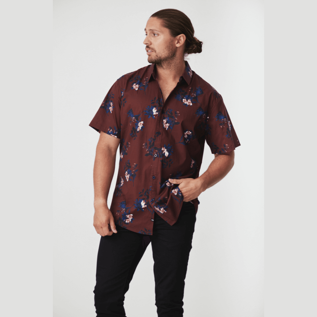 Stewarts Menswear Blackwood Apparel Scott Short Sleeve Shirt.The Blackwood Apparel Scott Short Sleeve Shirt is made from a blend of 97% cotton and 3% elastane. This shirt offers both breathability and flexibility. Rich burgundy coloured shirt with white and blue floral print all over. Photo shows model wearing Scott short sleeve shirt with black jeans.