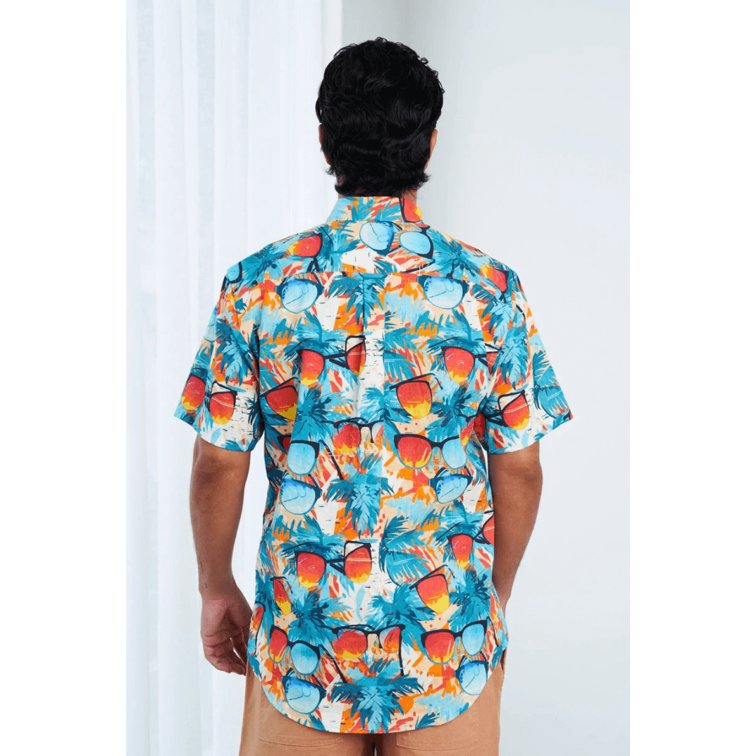 Back view of model wearing Men’s Hemp Cotton Resort Short Sleeve Shirt, natural hemp-cotton blend, available at Stewart’s Menswear Mullumbimby. Brightly coloured sunglasses pattern button through shirt.