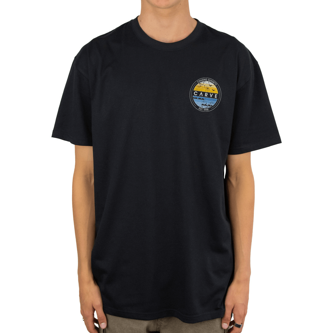 Stewarts Menswear Carve Boys Horizon Tee. This is a regular fit boy's short sleeve T-shirt with small chest print and large back graphic print with the words "Chasing Sunsets Est 1998). Colour is black. Image shows front print.