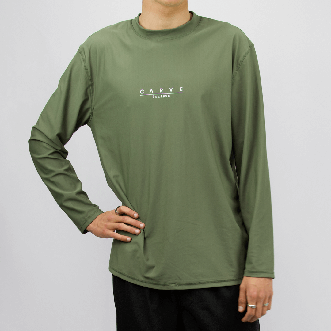 Carve Men’s Long Sleeve Swim Rashie. Relaxed-fit rash vest with UPF 50+ sun protection, available at Stewart’s Menswear Mullumbimby. Colour is khaki with small Carve print on front chest