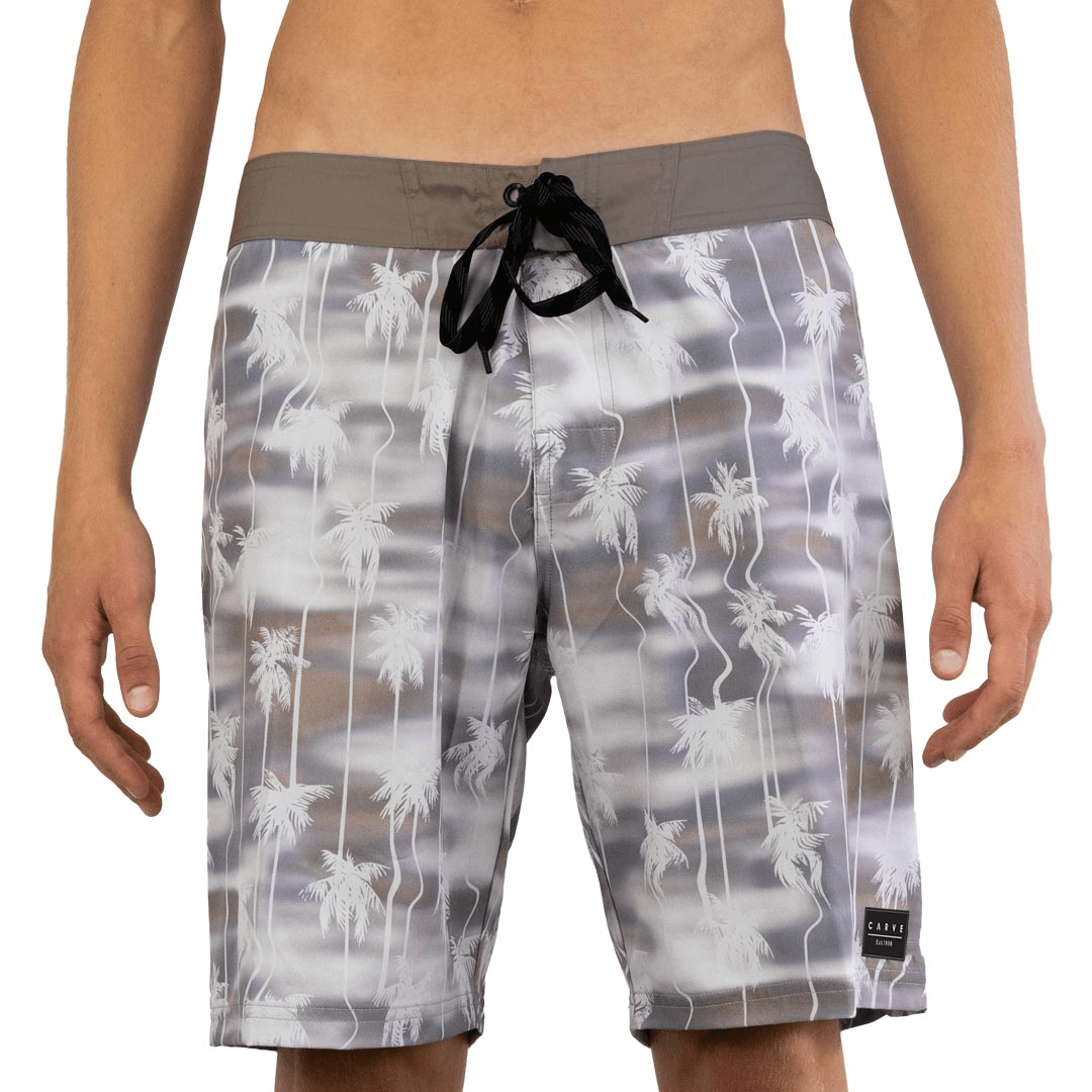 Stewarts Menswear Carve Palms Boardshort. Men's straight leg boardie with fitted waistline. Front tabs and draw cord, front elastane gusset fly and 19" leg length. Concealed zip pocket at back and carve logo badge on left leg. Sublimation print grey/khaki background with white palm trees.