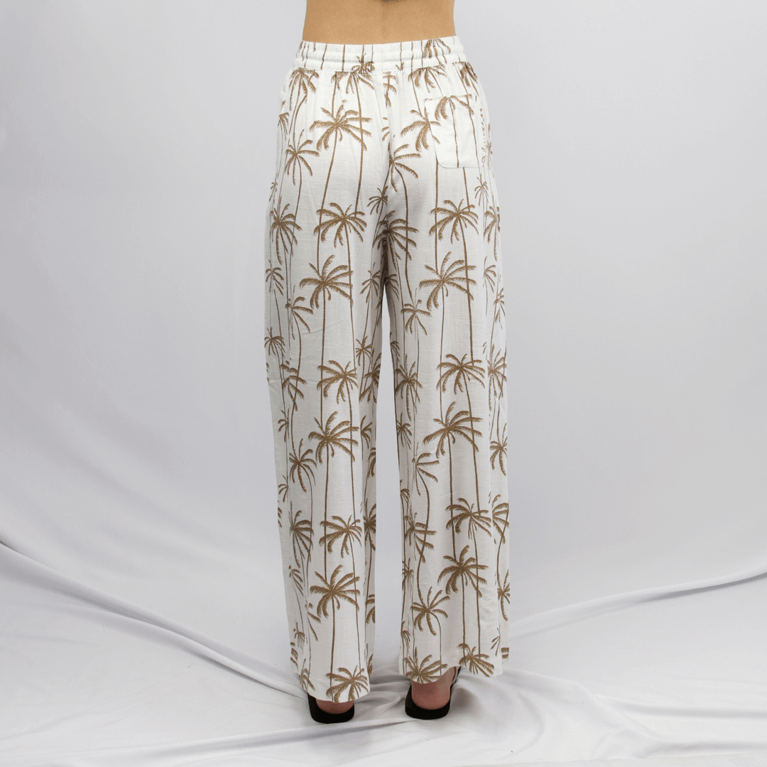 Back view of Carve Sobi Women’s Beach Pant, available at Stewart’s Menswear Mullumbimby. White and tan palm print linen-viscose relaxed fit beach pants.