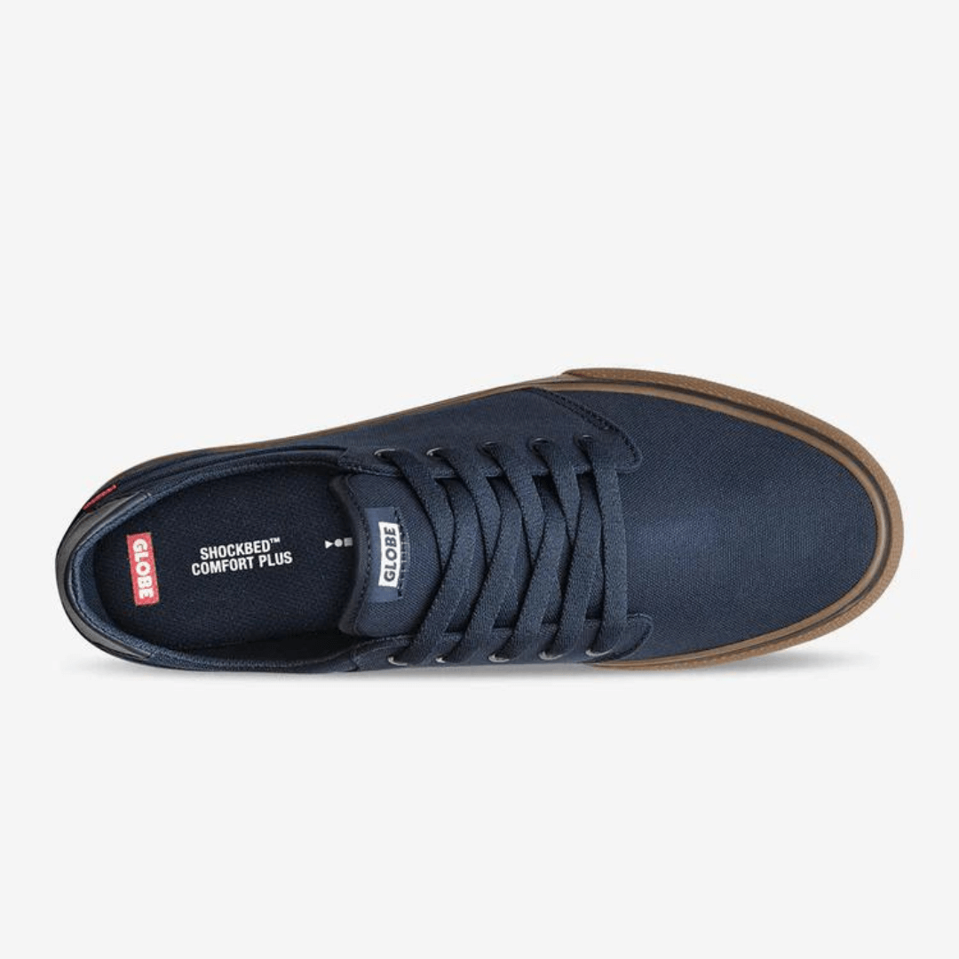 Stewarts Menswear Globe Goodstock Skate Shoe. The Globe Goodstock skate shoe in Navy/Gum is a classic Globe silhouette with a canvas upper. Lace-up, fully lined mainstay style featuring a Super V outsole for enhanced grip and board feel and a taller rubber foxing for maximum durability. Top is Navy canvas with Gum coloured sole. Photo shoes top view of shoe.