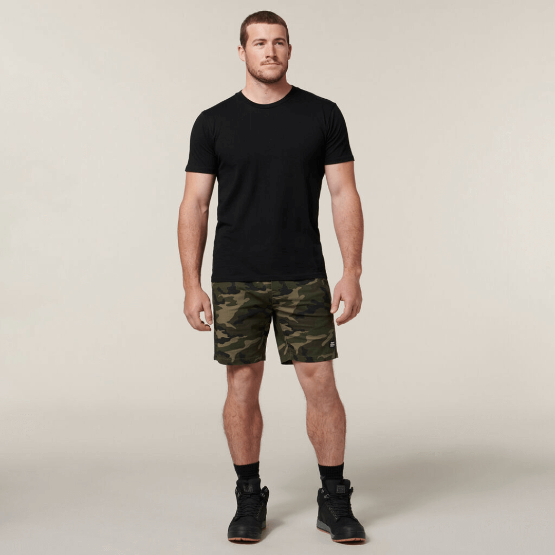 These stylish active Camo shorts are the perfect addition to your wardrobe. With an elastic waist and made from cotton rich stretch ripstop fabric, they are both comfortable and durable. Featuring a stylish on trend camo print, slim fit with plenty of pockets. Photo is full length shot of model wearing Hard Yakka Camo Active Shorts with a black t-shirt.