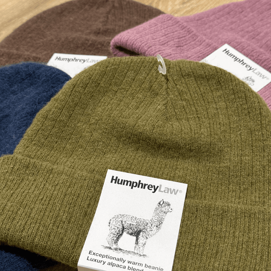 Collection of alpaca beanies with 'Humphrey Law' labels on a wooden surface.