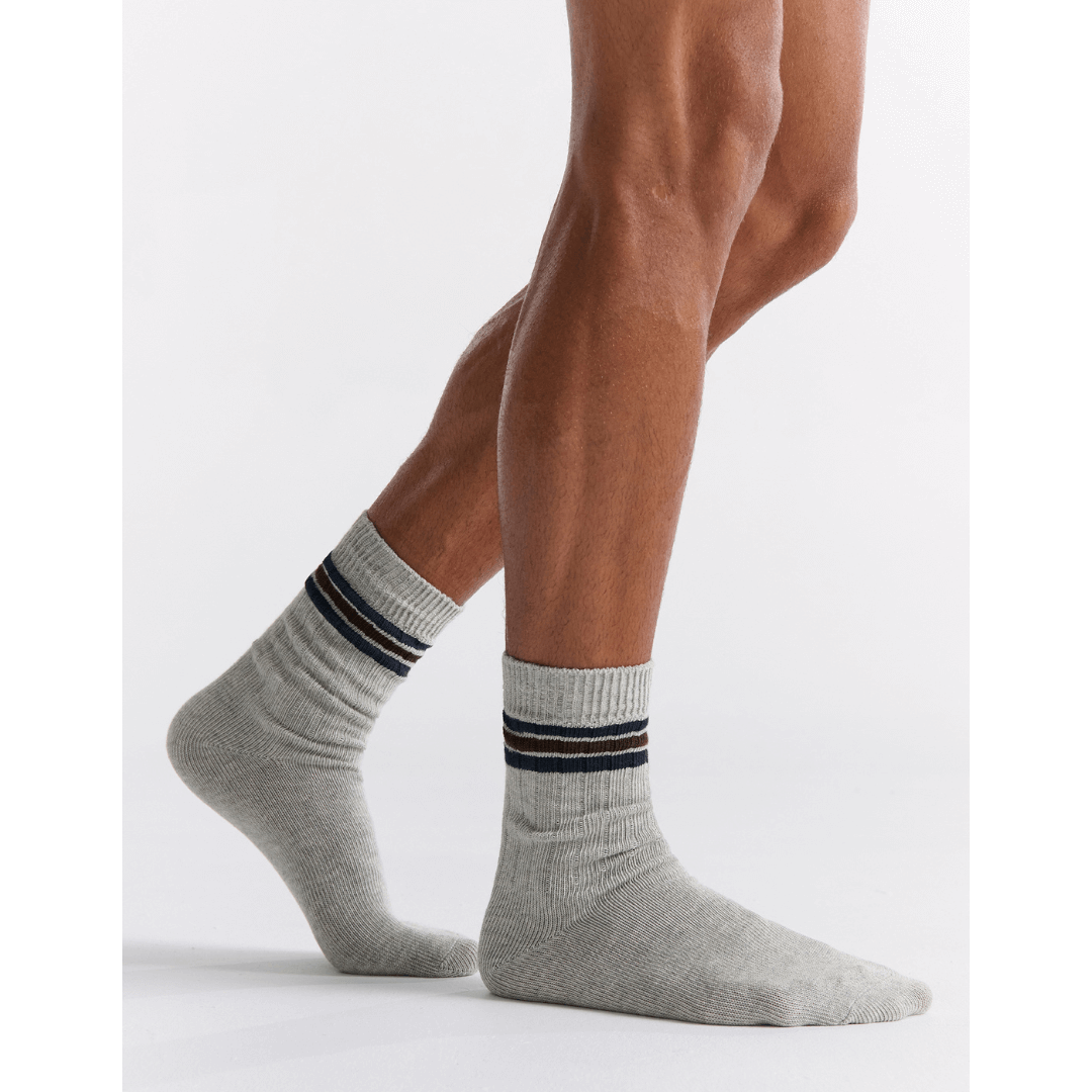 Stewarts Menswear Mullumbimby. Ambra Men's Chunky rib tennis stripe crew socks. Organic Cotton socks. Grey Marle colour with three stripes at top (2 x Navy with 1 x brown in between). Photo shows model wearing Ambra men's chunky rib tennis crew socks in Grey.