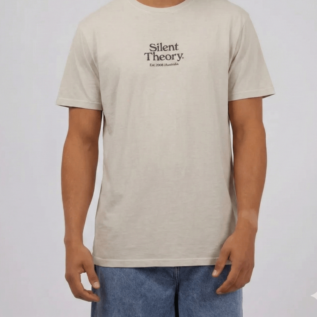 Model wearing Silent Theory Classic Embroidered tee available from Stewart's Menswear Mullumbimby. Light grey tee with embroidered Silent Theory logo on front chest.