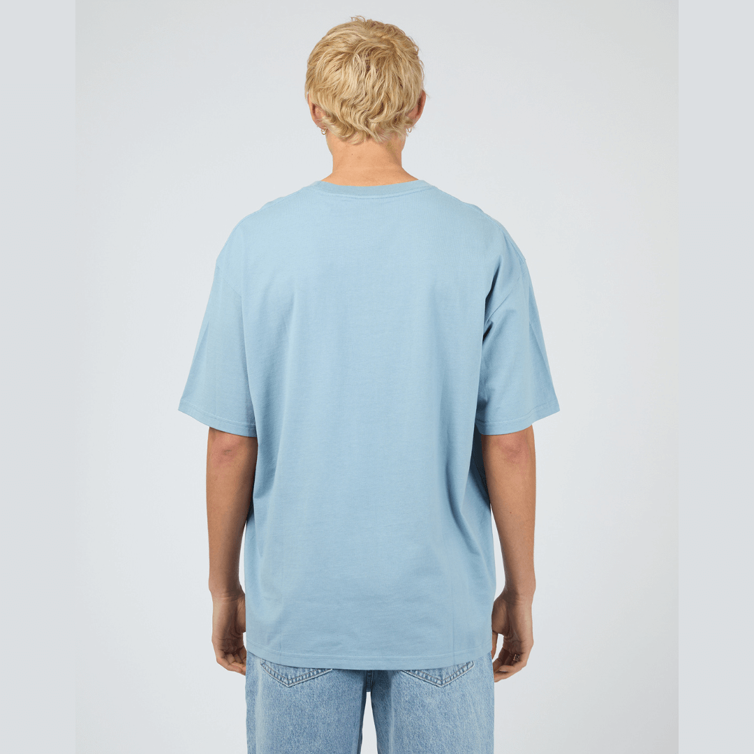 Back view of model wearing blue Silent Theory Essential Tee available at Stewart’s Menswear Mullumbimby. Men’s relaxed fit 100% cotton tee with crew neck and short sleeves.