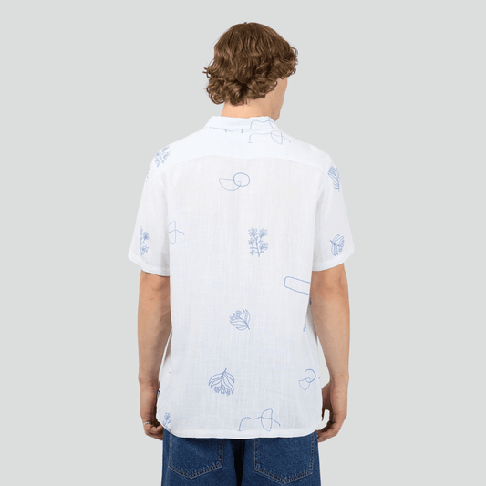 Back view of a person wearing a St Goliath Ceramic shirt, a white short sleeve shirt with blue patterns on a plain background. Available at Stewart's Menswear, Mullumbimby.