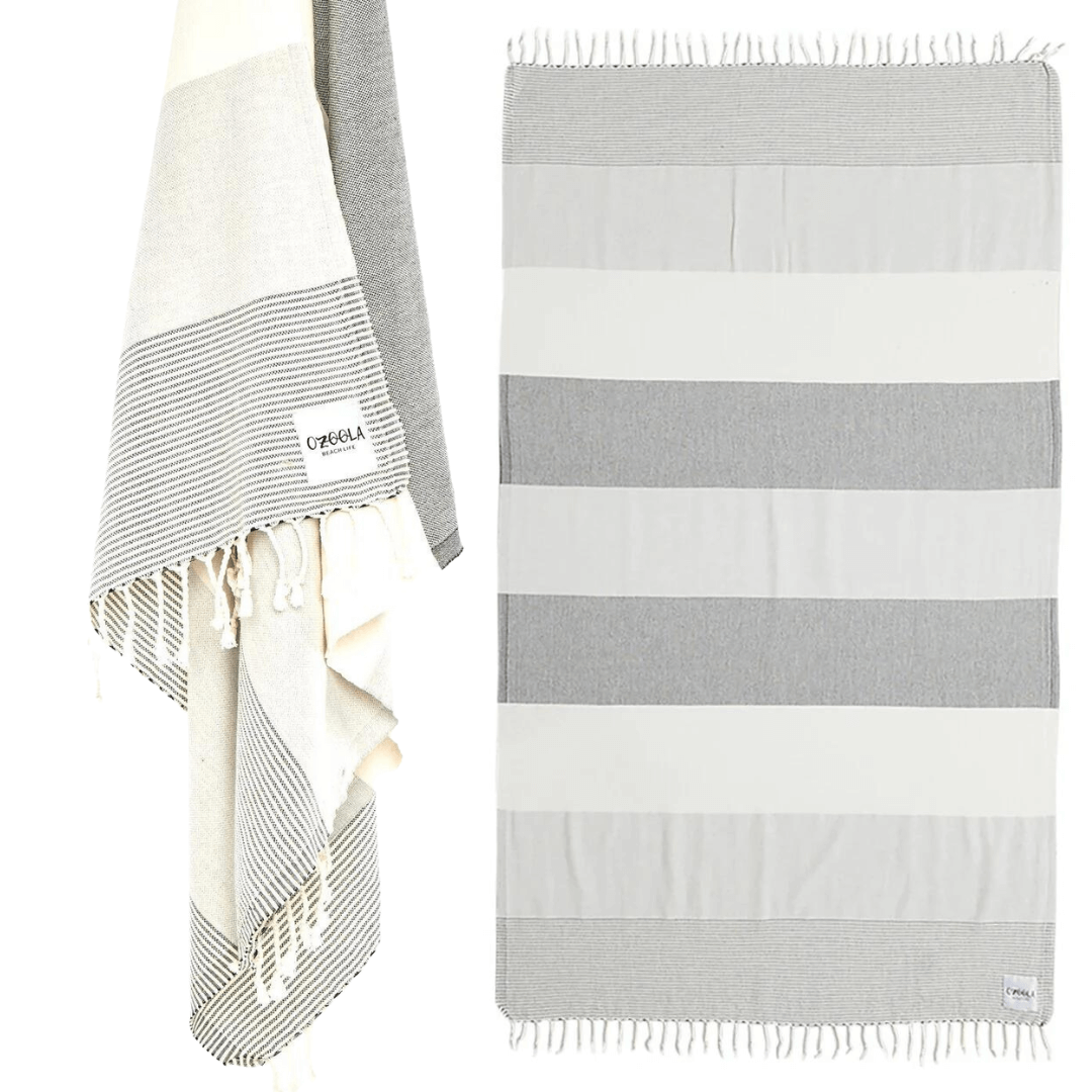 Stewarts Menswear Ozoola Johnny Towel. The Johnny Towel is made from 100% Turkish Cotton which is super absorbent and fast drying.  Sized at 180 x 100cm with knotted fringing at each end. Ideal for endless beach days, and lazy pool days.  Soft and light, it is perfect for travelling and it can also be used as a sarong.  Colour is Natural Grey with wide stripes of constrast colours.