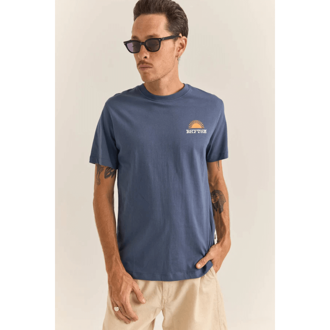 Stewarts Menswear, Mullumbimby. Rhythm Livin Awake Tee-shirt. Colour is blue. Photo shows model wearing Rhythm Awake T-shirt, front view. Rhythm logo with sun print on left chest.