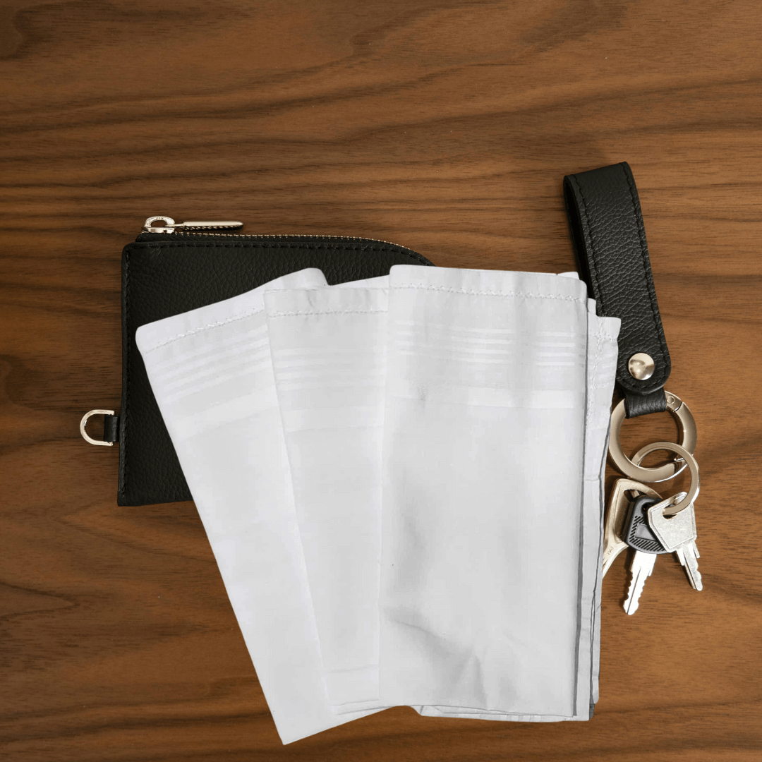 Stewart's Menswear, Mullumbimby. Rosdale men's white handkerchiefs sold as single units. Photo shows 3 white hankies sitting on a timber bench with men's wallet and keys.