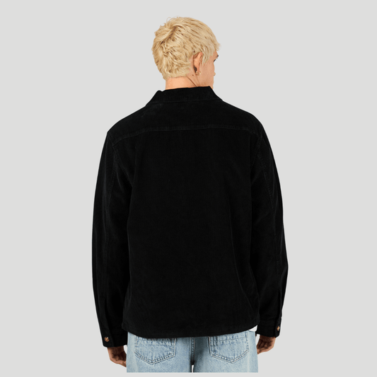 Back view of man wearing a black corduroy shirt and light blue jeans on a gray background. Silent Theory Jameson Cord Shirt in cotton corduroy available at Stewart’s Menswear Mullumbimby.