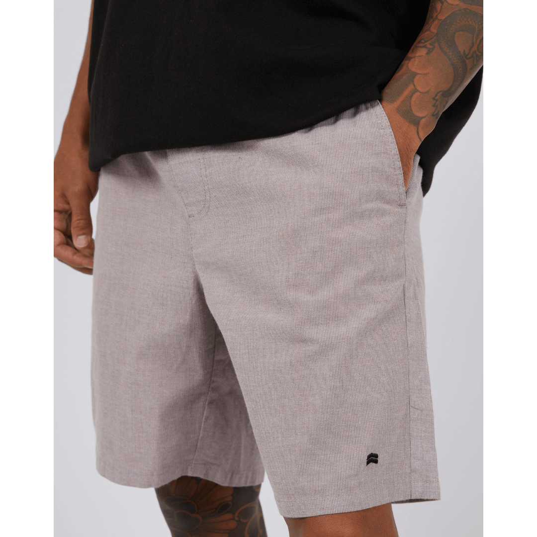 Stewarts Menswear St Goliath Dune Short. A light coloured knee-length elastic waist short with a very fine brown stripe running through. Photo shows close up of model wearing St Goliath Dune Short.