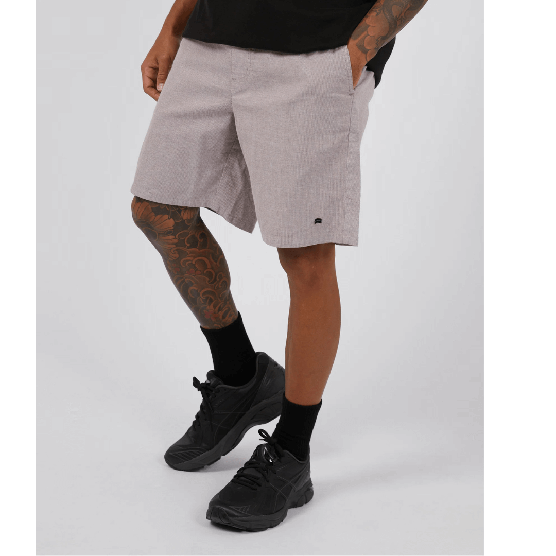 Stewarts Menswear St Goliath Dune Short. A light coloured knee-length elastic waist short with a very fine brown stripe running through. Photo shows front view of model wearing St Goliath Dune Short.