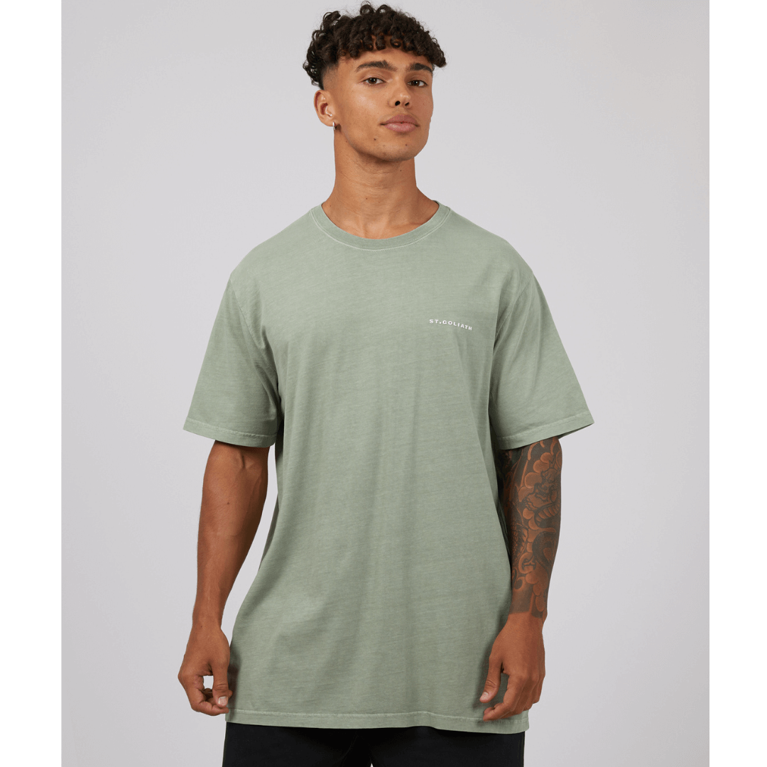 Stewarts Menswear St Goliath Essential tee. Photo shows model wearing Fig Green coloured St Goliath Essential Tee. Small raised rubber logo on left chest.