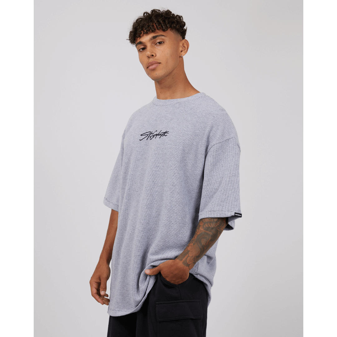 Stewarts Menswear St Goliath Texture Tee. A light coloured t-shirt featuring St Goliath logo embroidered in black. Photo shows model wearing St Goliath Texture Tee. Side View.