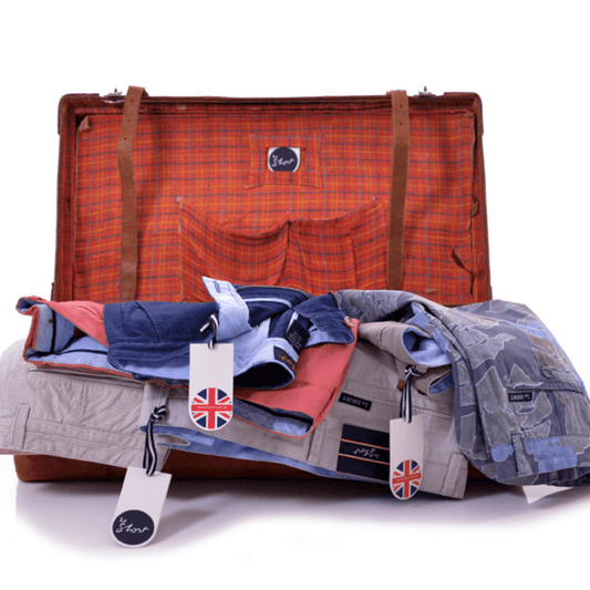 Stewarts Menswear Le Short Stretch Cotton shorts. Lifestyle photo shows a selection of shorts spilling out of a suitcase.