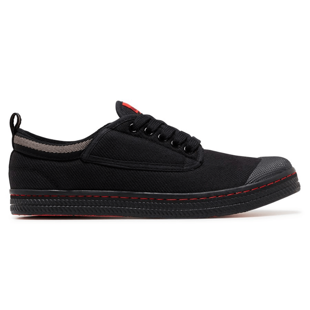 Stewart's Menswear Dunlop Volley Classic shoe. Whether you're dressing up or down, Dunlop Volleys are versatile and will add retro style to your outfit. The simple design features a canvas upper with a moulded rubber toe cap and a contrasting stripe on the side. The shoe's original herringbone rubber outsole is slip resistant and non-marking. Black side view
