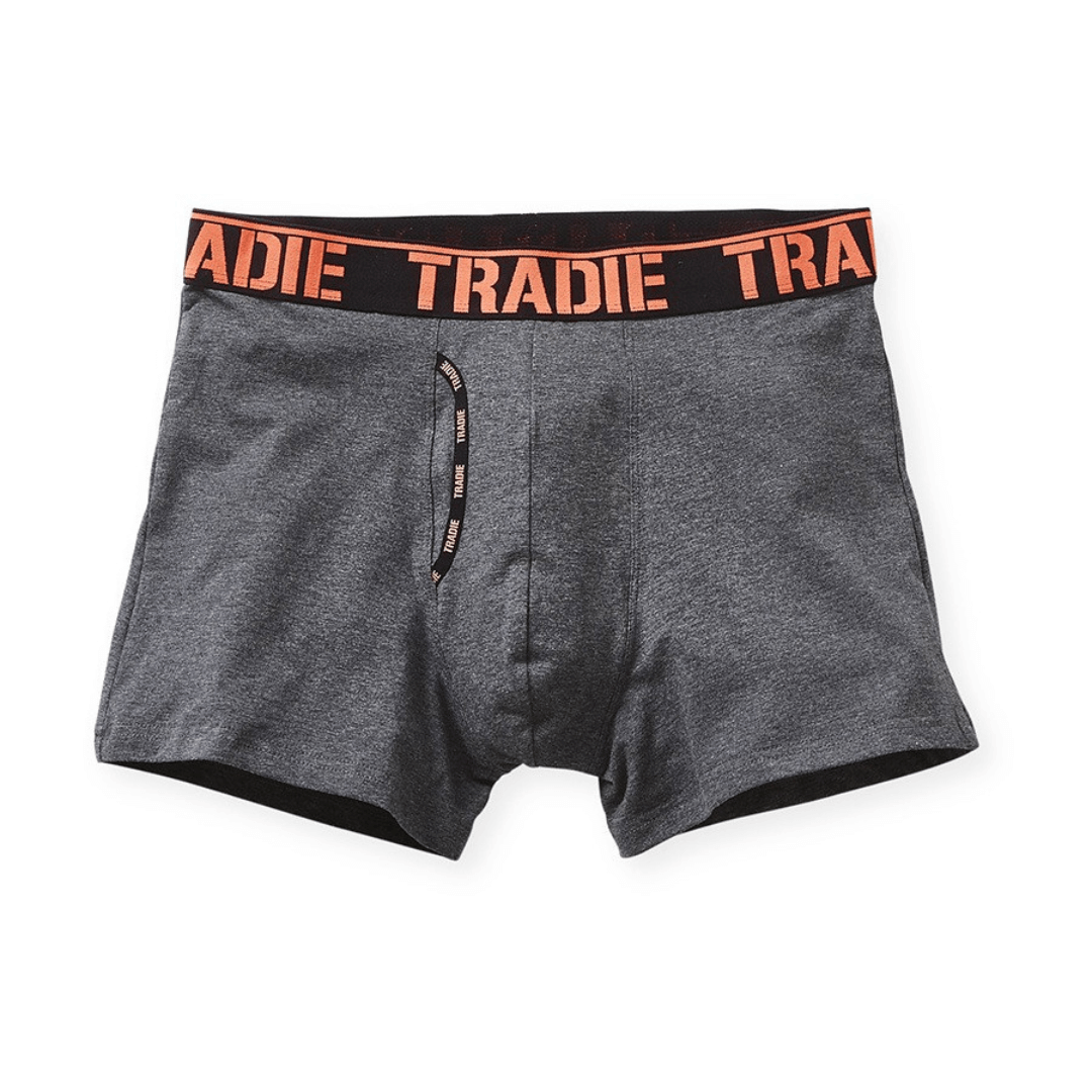 Stewart's Menswear Tradie man front trunk. Tradie Man Front Trunk is made from a blend of cotton and elastane, great for everyday wear.  The soft jacquard elastic waistband ensures a comfortable fit, while the working fly provides easy access.  The stretch cotton fabric is durable and designed to move with you. Photo of Charcoal Marle trunks with black waistband. Tradie logo printed around band in Coral Colour.