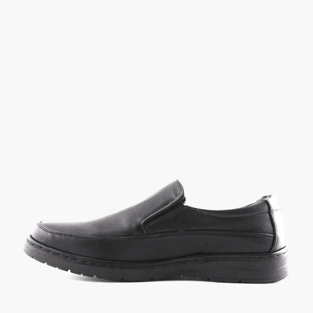 Stewart's Menswear Woodlands Shortall men's slip on shoe.Shortall by Woodlands is a men's slip-on shoe which features a rounded toe silhouette. It has an arched low rubber outsole and heel support plus a full insole cushioned foot bed. Man-made upper, lining and sole. Side view, Colour is black.