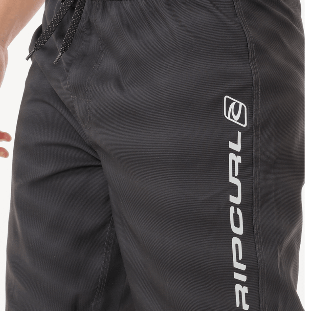Shock Easy Fit 21" Boardshort  available at Stewart’s Menswear Mullumbimby. Men’s recycled polyester boardshort with elastic waistband and engineered print. Photo shows close up view, colour is black.