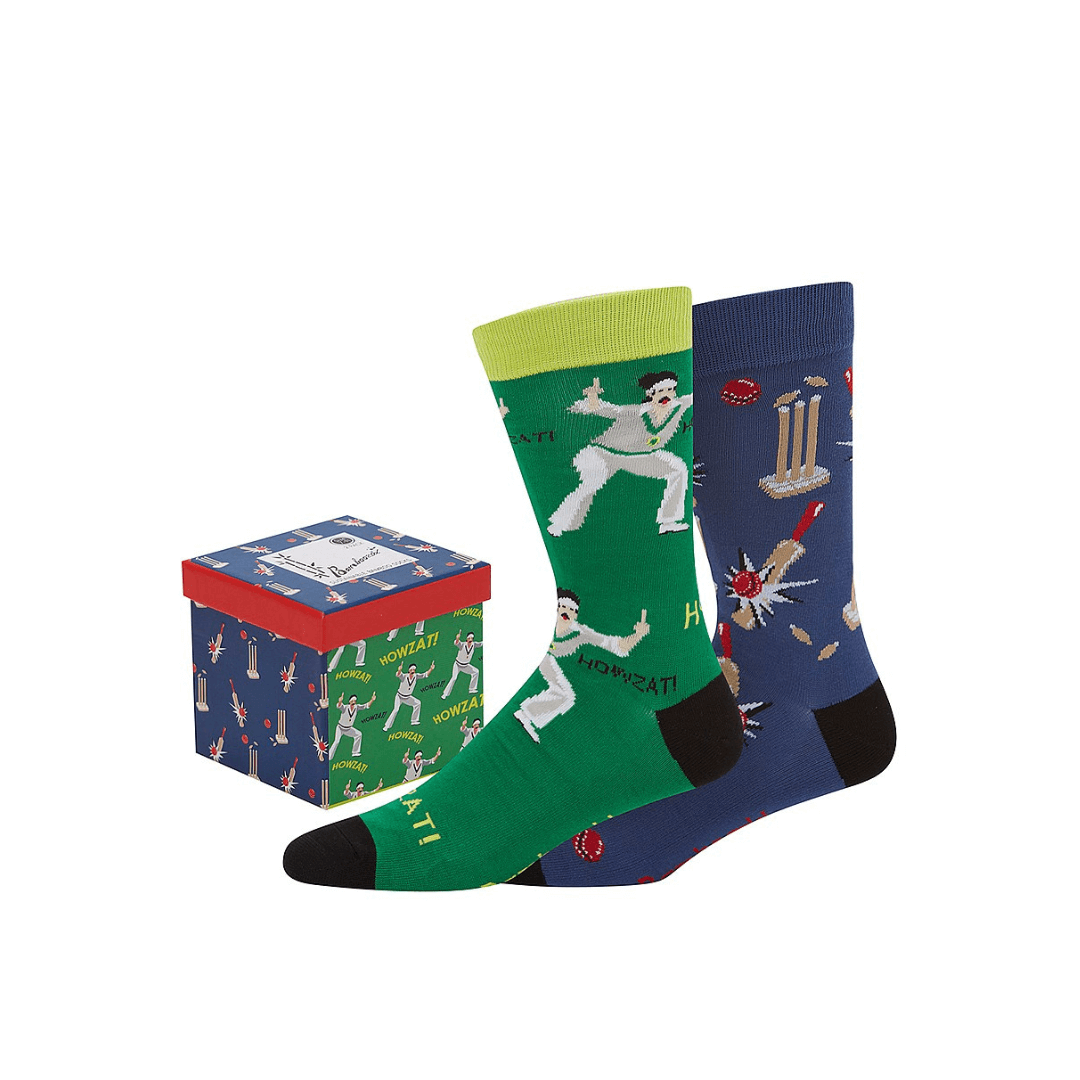 Stewarts Menswear Bamboozled socks 2 pack gift box. This Gift Box is the perfect gift, featuring two pairs of novelty crew socks packaged in a matching Gift Box.  Bamboozld Gift Boxes have a vibrant collection of quirky bamboo-blend socks which pack a playful punch. Theme is Cricket. Includes one x navy socks with wickets/bats, one x green socks with player Howzat!