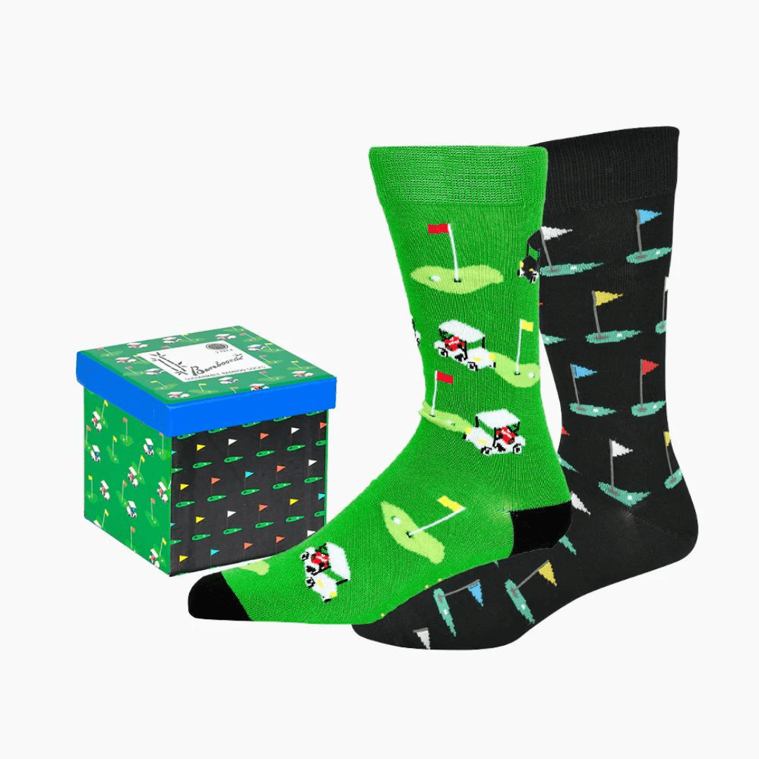 Stewarts Menswear Bamboozled socks 2 pack gift box. This Gift Box is the perfect gift, featuring two pairs of novelty crew socks packaged in a matching Gift Box.  Bamboozld Gift Boxes have a vibrant collection of quirky bamboo-blend socks which pack a playful punch. Theme is Golf. Includes one x black socks and one by green socks.