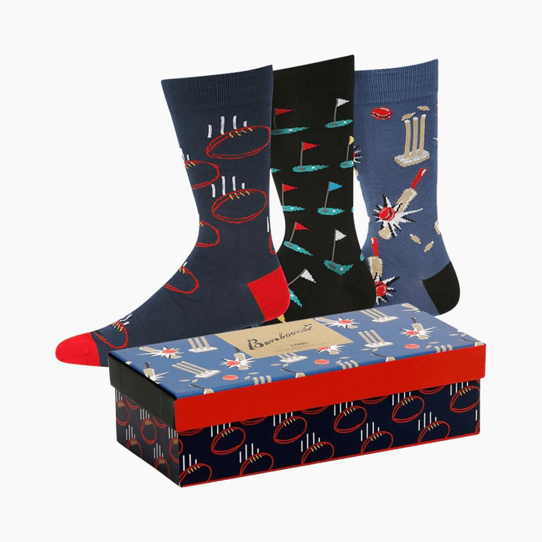 Stewarts Menswear Bamboozled socks 3 pack gift box. This Gift Box is the perfect gift, featuring three pairs of novelty crew socks packaged in a matching Gift Box.  Bamboozld Gift Boxes have a vibrant collection of quirky bamboo-blend socks which pack a playful punch. Theme is sport with 2 x blue socks, 1 x black socks featuring different sport print on each pair - AFL, Golf and Cricket.
