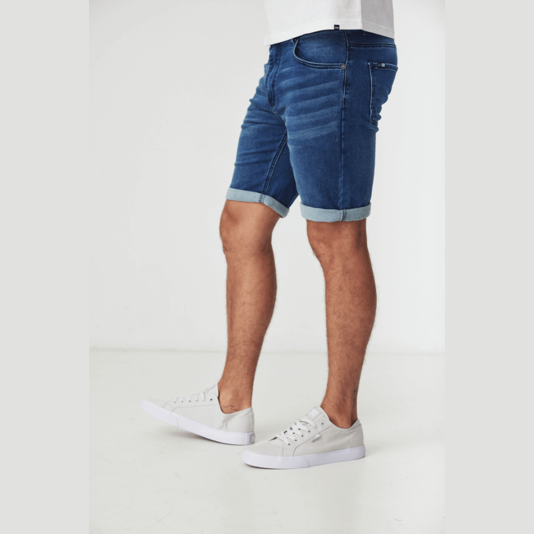 Stewarts Menswear Blackwood Apparel Perth Denim Shorts. Photo shows model wearing Perth denim shorts, colour is medium blue, side view. Can be worn rolled up or down.