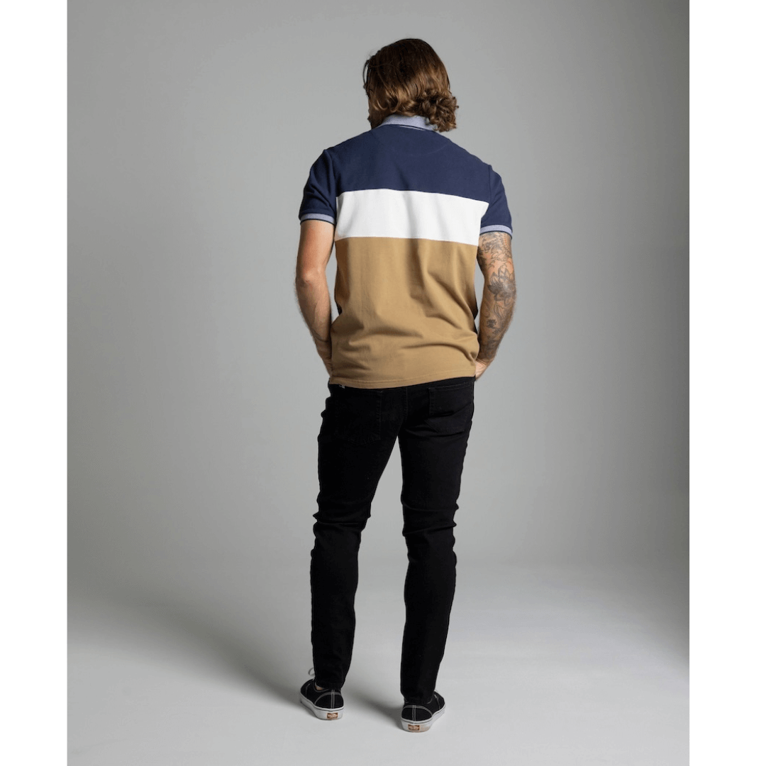 Stewart's Menswear Blackwood Apparel Waggs Lifestyle polo shirt. The Blackwood Apparel Waggs Lifestyle short sleeve polo is made from 100% cotton. Its colour block design in tobacco, navy and white gives it a casual sophistication. Photo shows model wearing Blackwood Waggs Polo Shirt back view.