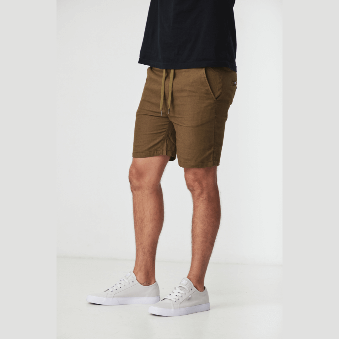 Stewarts Menswear Blackwood Apparel Ziggy linen shorts. made from a blend of 52% linen and 48% cotton. With an elastic waist and drawcord for a personalised fit. Photo shows model wearing Ziggy linen shorts with a black t-shirt. Colour is Khaki, front view.