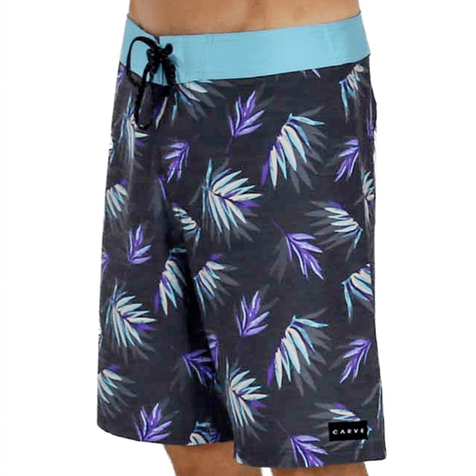 Carve Mullum Boardshorts in charcoal print with purple, aqua, and white palm leaves and an aqua waistband, available at Stewart’s Menswear Mullumbimby.