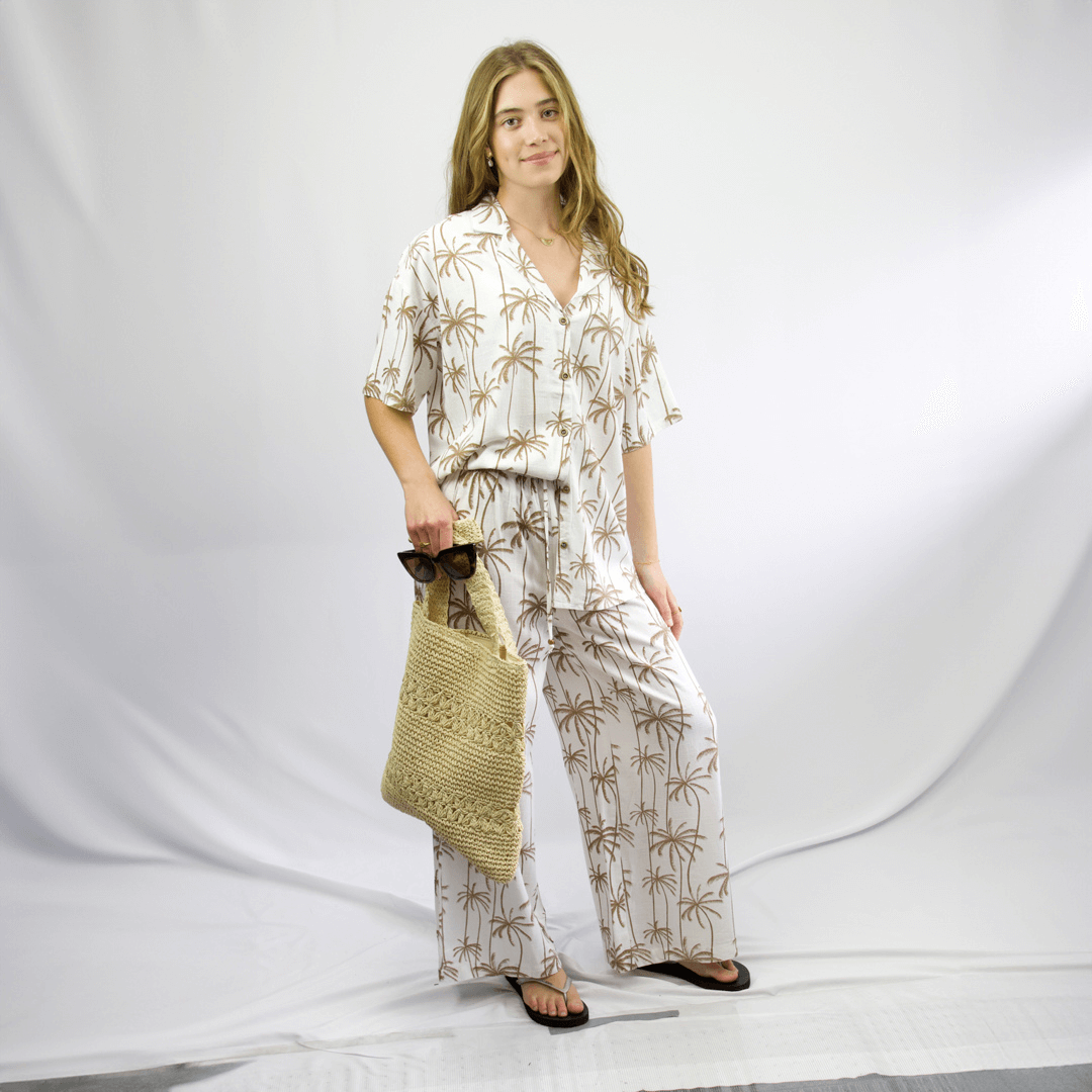 Mix and Match view of Carve Sobi Women’s Beach Pant, available at Stewart’s Menswear Mullumbimby. White and tan palm print linen-viscose relaxed fit beach pants teamed with Sobi Beach Cover Up.