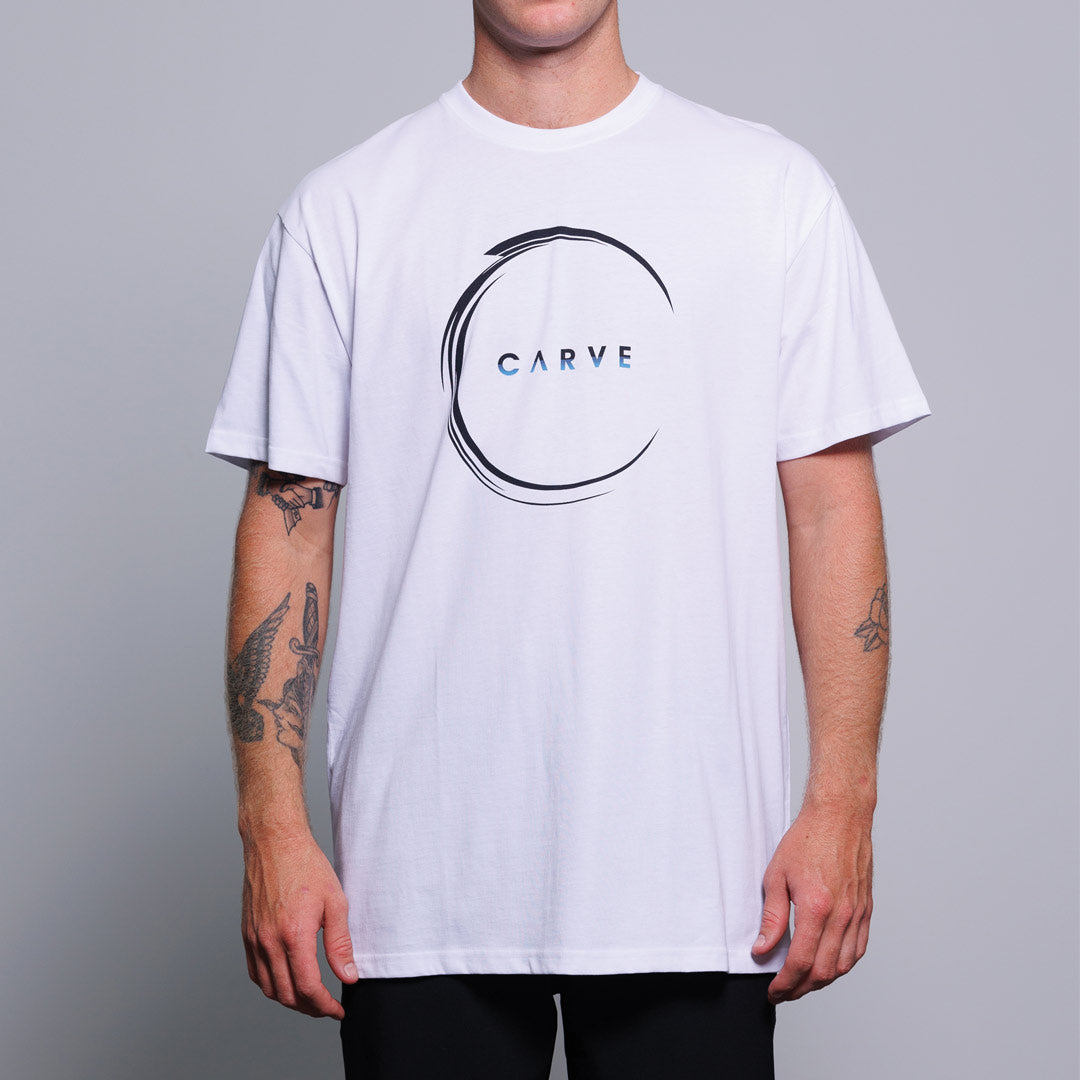 Stewarts Menswear Carve Surfwear Backwash Tee. This is a regular fit men's short sleeve T-shirt with simple Carve graphic centre chest print. Image shows model wearing white tee. Circular black graphic with mini carve logo inside.