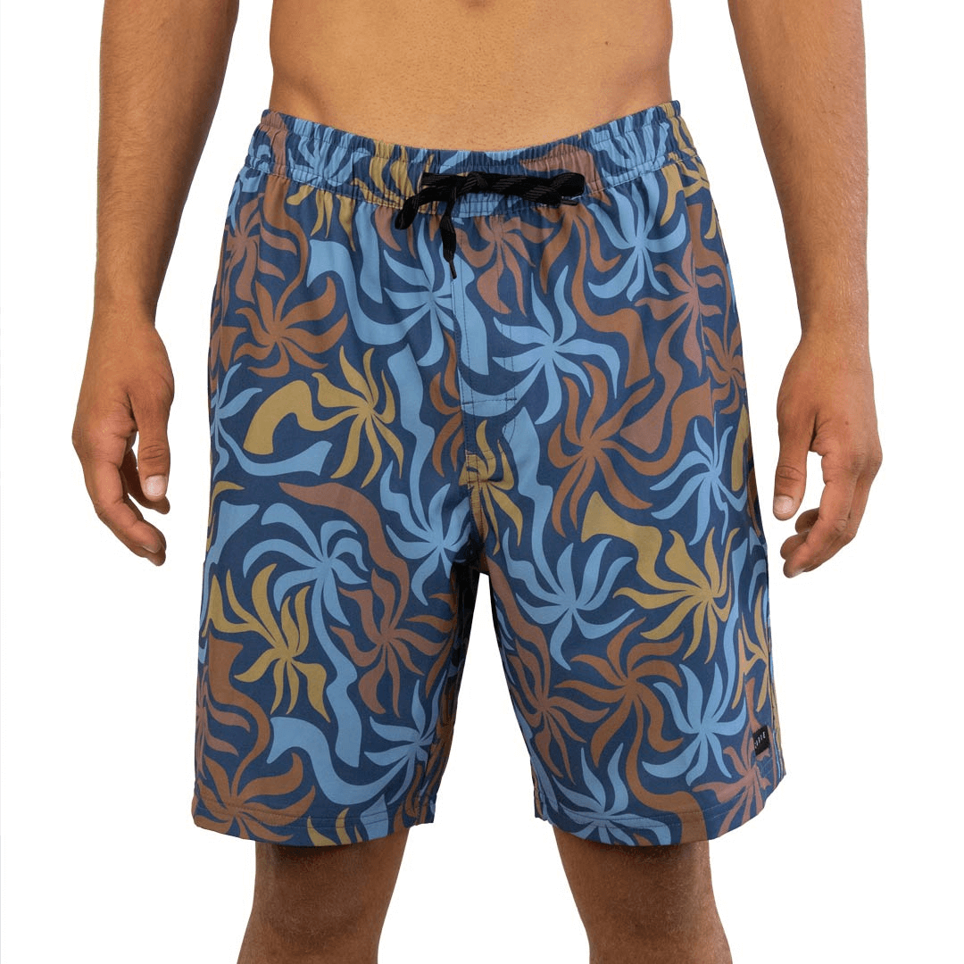 Stewart's Menswear Carve Twisted Palms Boardshorts. Comfort fit with a 18" outer leg length and an elastic waistline with drawcord and mock fly front.  Features side seam pockets, plus keep your essentials safe with the back velcro closure pocket. All over sublimation print of abstract pandanus palms in brown, light blue and mustard on a darker blue background.