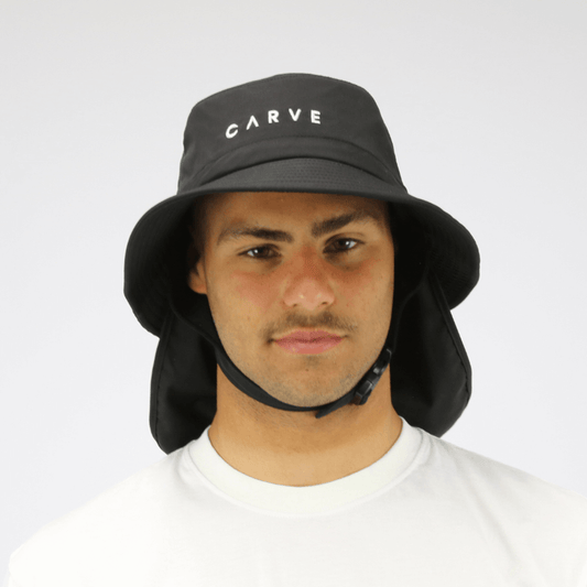 Model wearing black coloured Carve Surf Hat available at Stewart’s Menswear Mullumbimby. Unisex quick-dry surf bucket hat with chin strap and detachable sun flap.