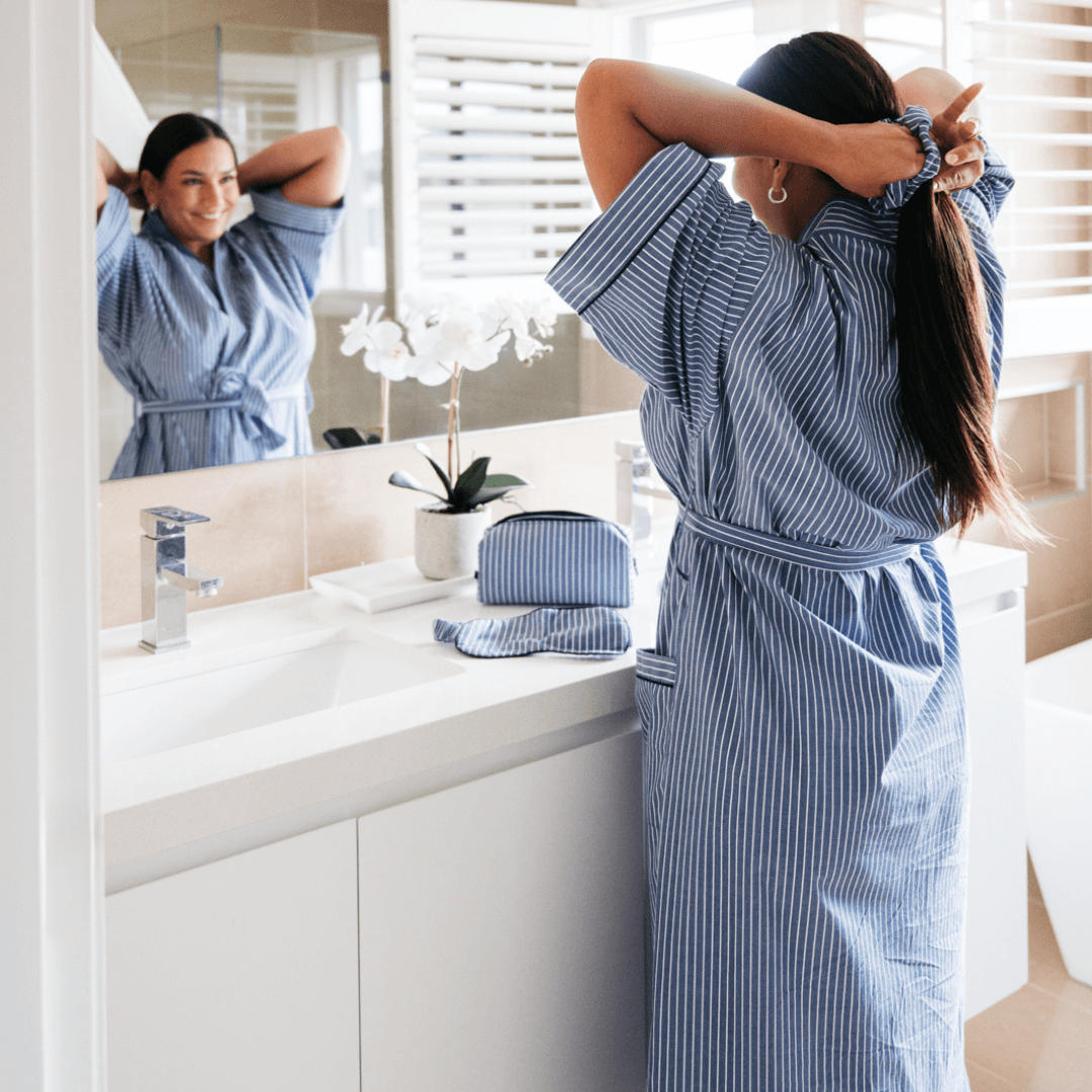 Adult female wearing Contare Unisex Refined Poplin Longer Length Kimono Robe in Denim Stripe, a cotton kimono robe with piped pockets and belt, available at Stewart's Menswear Mullumbimby.