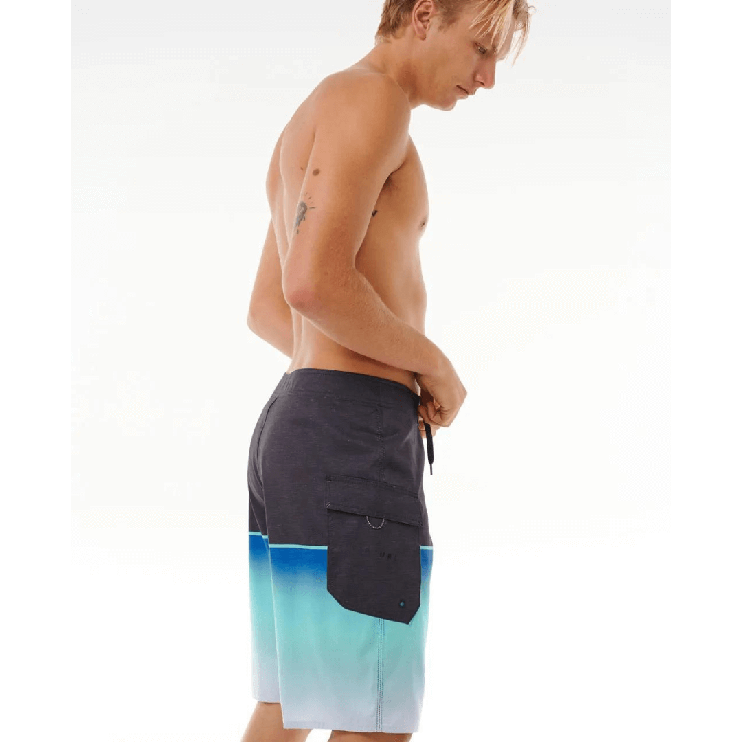 Stewart's Menswear Rip Curl Dawn Patrol Boardshorts. Black top half with gradient blue bottom half. Photo shows side view of model wearing boardshorts.