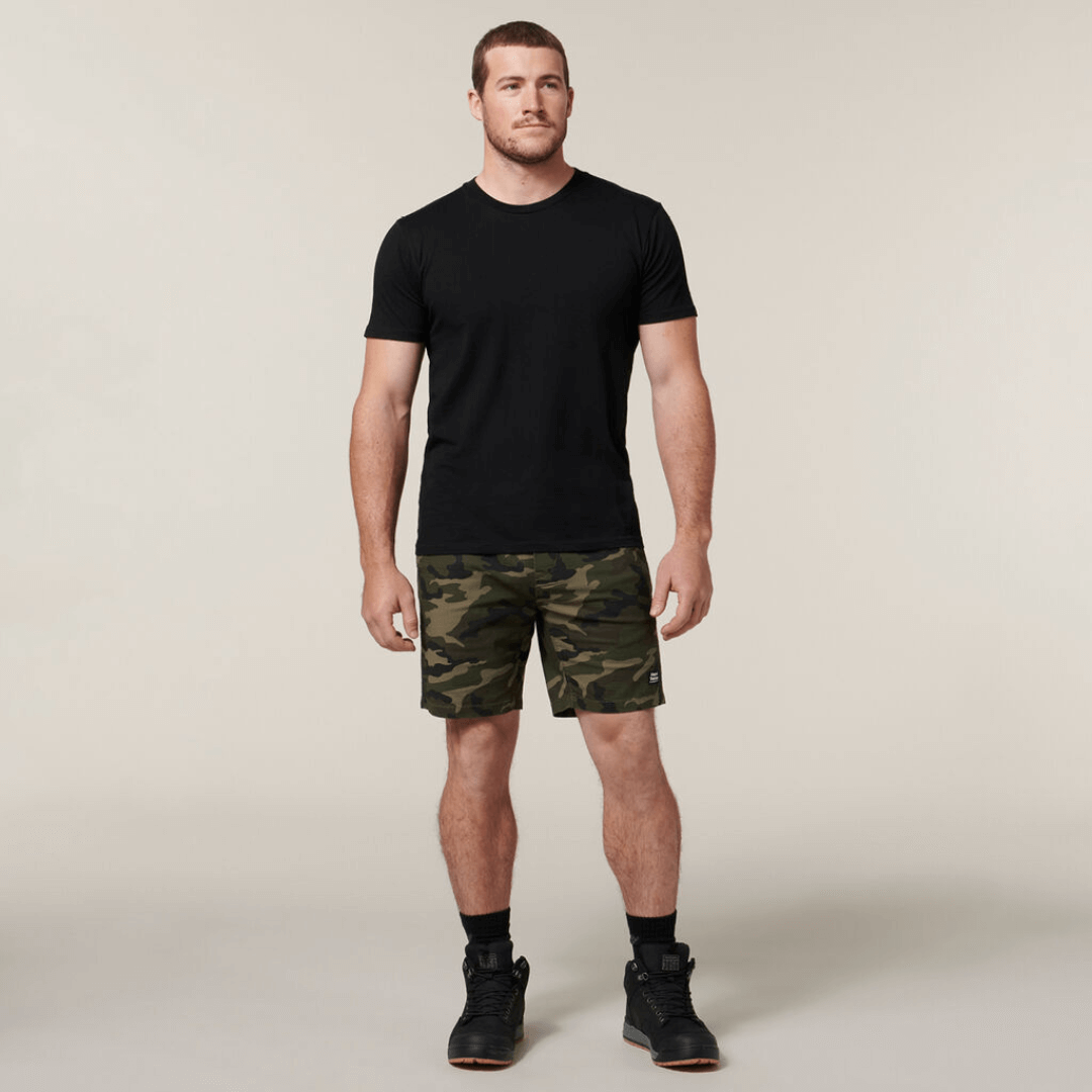 These stylish active Camo shorts are the perfect addition to your wardrobe. With an elastic waist and made from cotton rich stretch ripstop fabric, they are both comfortable and durable. Featuring a stylish on trend camo print, slim fit with plenty of pockets.  Photo is full length shot of model wearing Hard Yakka Camo Active Shorts with a black t-shirt.