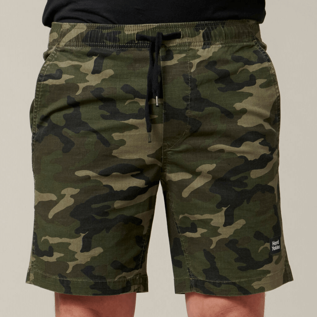 Stewarts Menswear Hard Yakka Camo Active Shorts. These stylish active Camo shorts are the perfect addition to your wardrobe. With an elastic waist and made from cotton rich stretch ripstop fabric, they are both comfortable and durable. Featuring a stylish on trend camo print, slim fit with plenty of pockets. Photo shoes close up photo of model wearing Hard Yakka Camo Active Shorts.