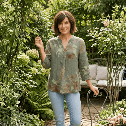 Woman wearing a khaki floral linen top with a gold button detail, paired with denim jeans. Harlow Lane linen top in khaki available from Stewart's Menswear in Mullumbimby