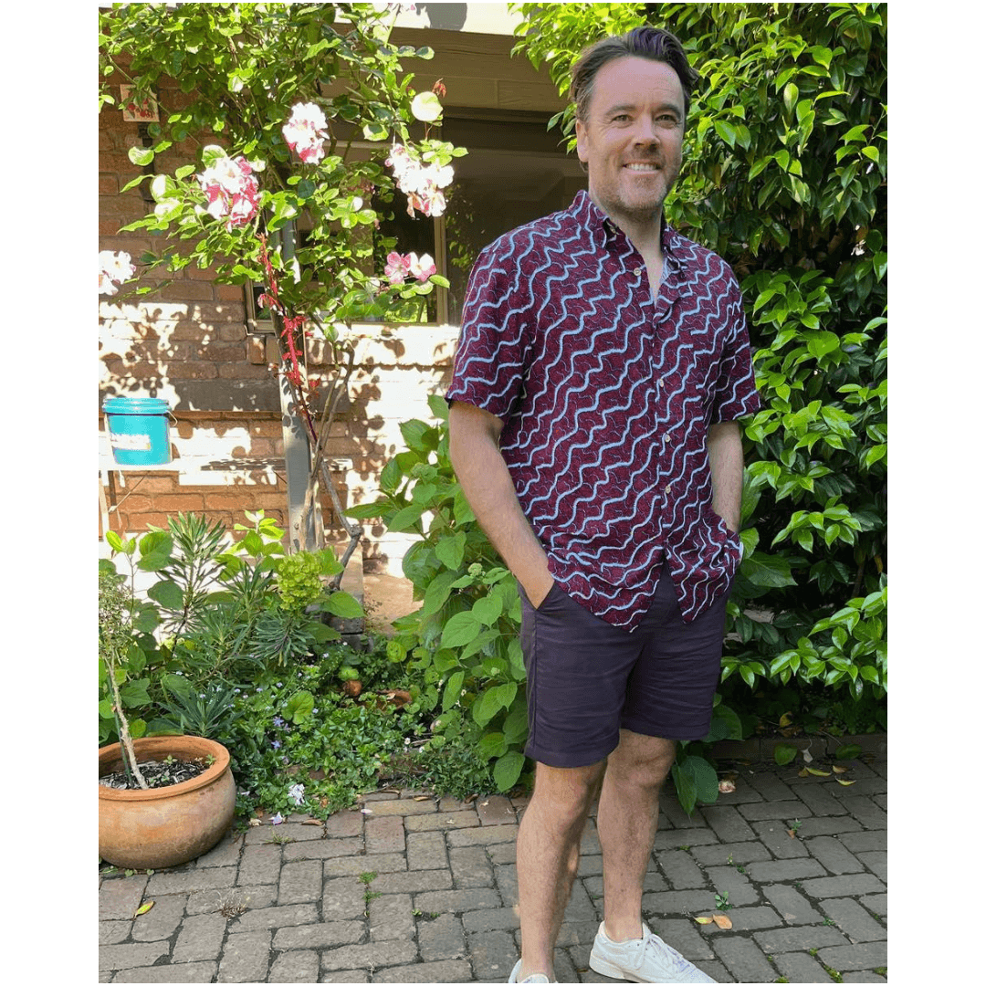 Man standing outdoors in a garden wearing kingston Grange Bamboo Dreaming shirt - Snake Dreaming.