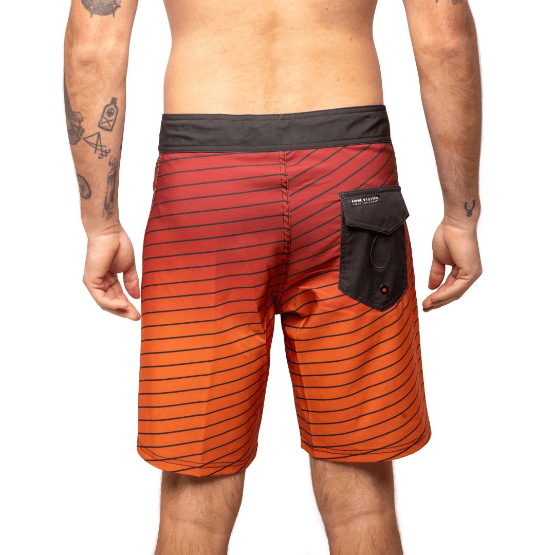 Stewarts Menswear Liive Apparel Cartesian Boardshort. Fitted waist with drawcord, back patch pocket with velcro closure and key loop in the back pocket. Charcoal waistband. Trendy gradient colour design in red/orange shades with charcoal stripe all over. Charcoal back pocket. Back View.