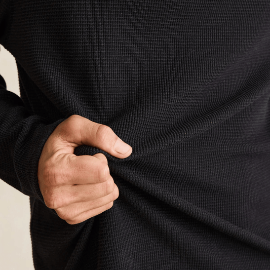 Close-up of a man wearing the Rhythm Classic Waffle Knit jumper in vintage black, showing the waffle knit texture.