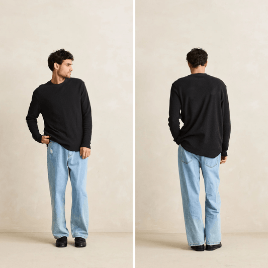 A man modeling a black long-sleeve crewneck sweater with light blue jeans, shown in a front-facing and back-facing side-by-side studio pose against a warm beige background.