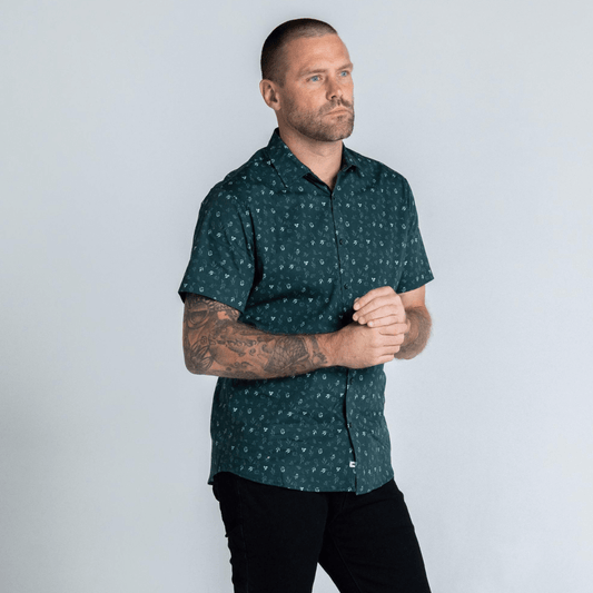 Stewart's Menswear, Mullumbimby. Photo shows model wearing Glass Short Sleeve shirt by Blackwood apparel. Front View. Colour is dark green with small floral print in lighter contrasting green colours.